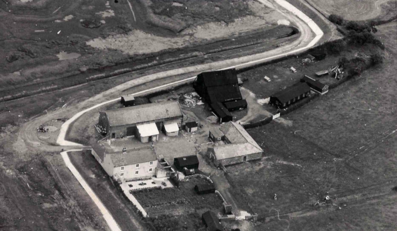Black-and-white aerial photograph of the farm buildings, courtyard and surrounding fields