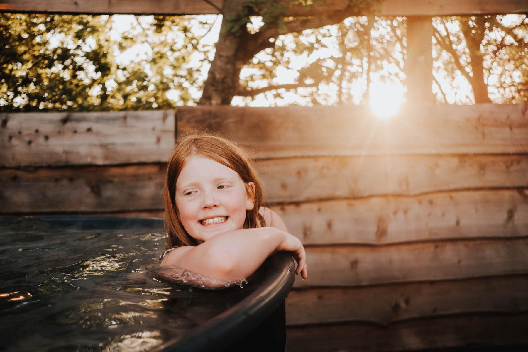 A guest enjoying the outdoor hot tub in the evening sunshine
