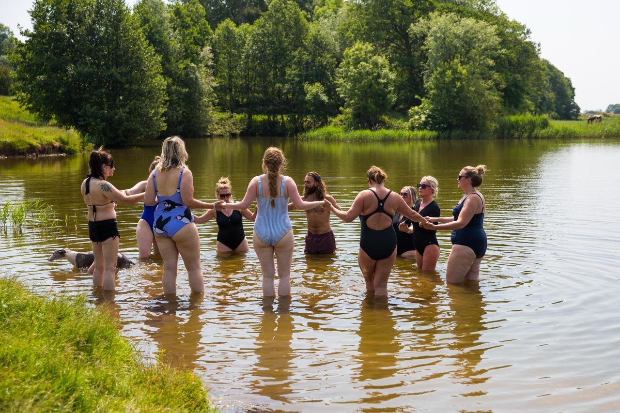 A group holding hands in the shallow water during an outdoor swimming experience