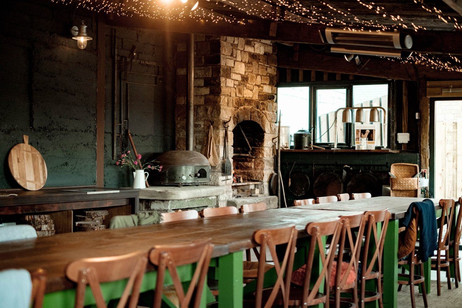 The long dining table and open fireplace in The Out Barn